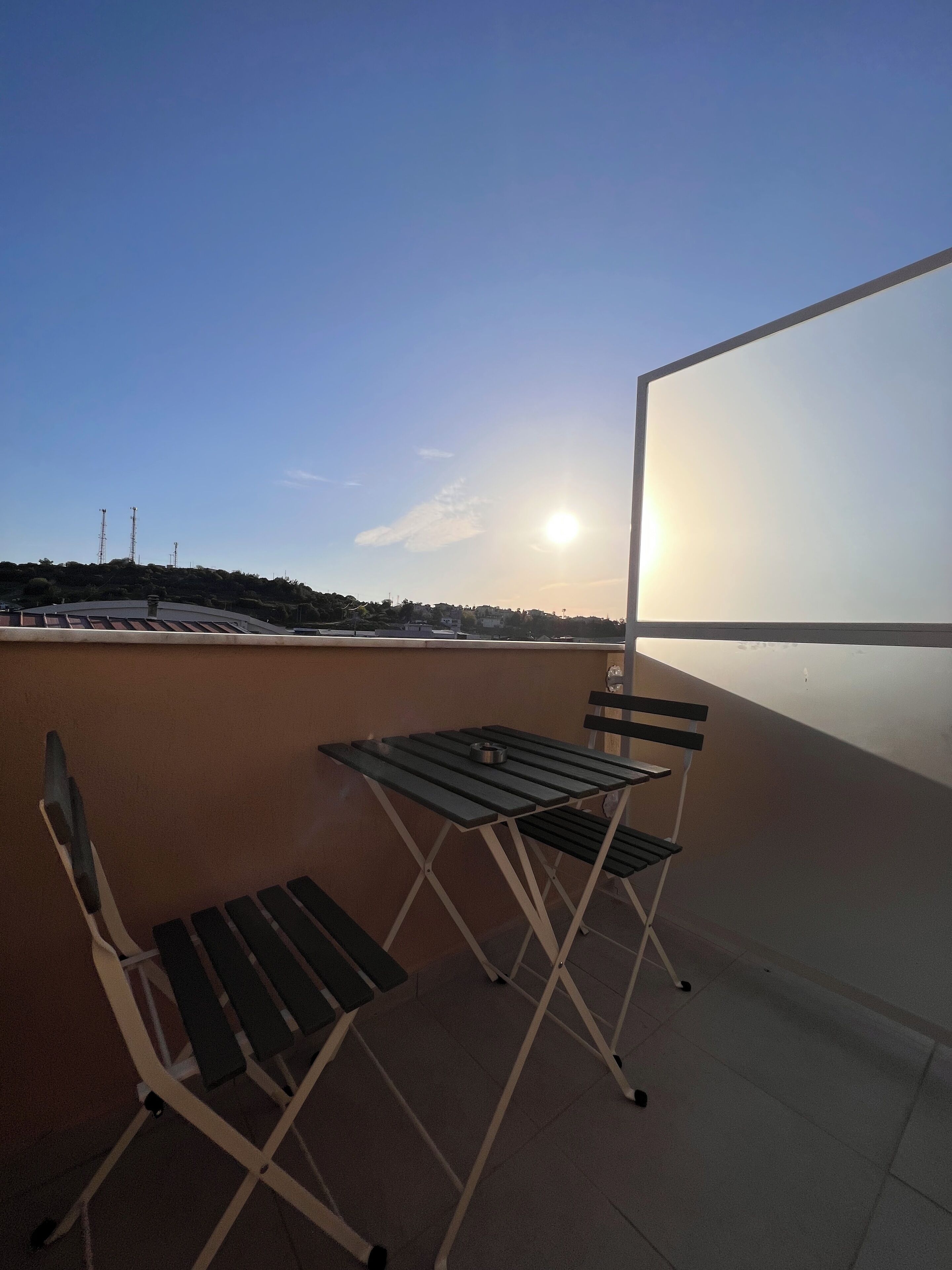 Terraza en la azotea con una mesa y sillas, cielo despejado y atardecer.