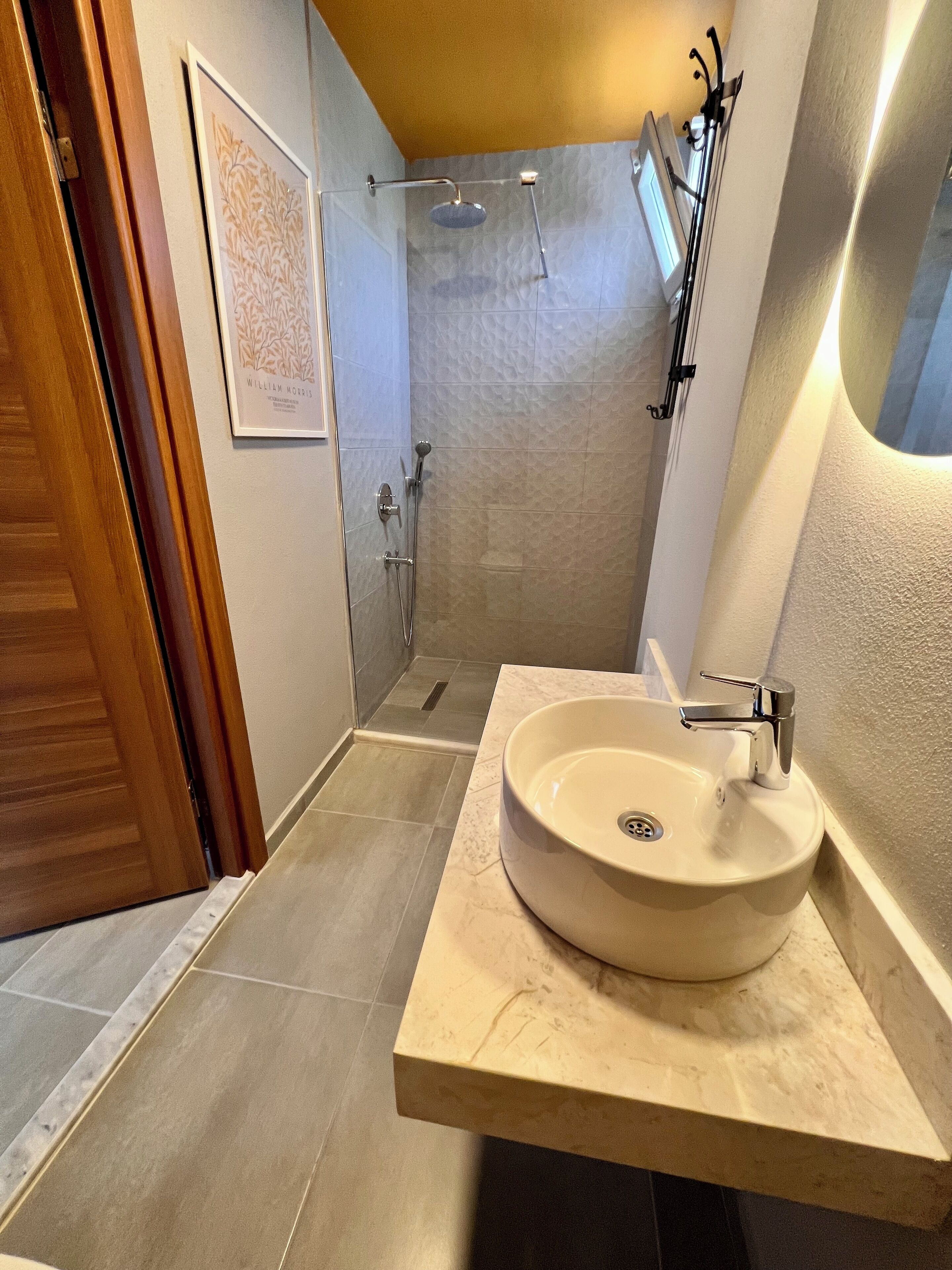 A bathroom with a large sink, shower, and a framed picture on the wall.