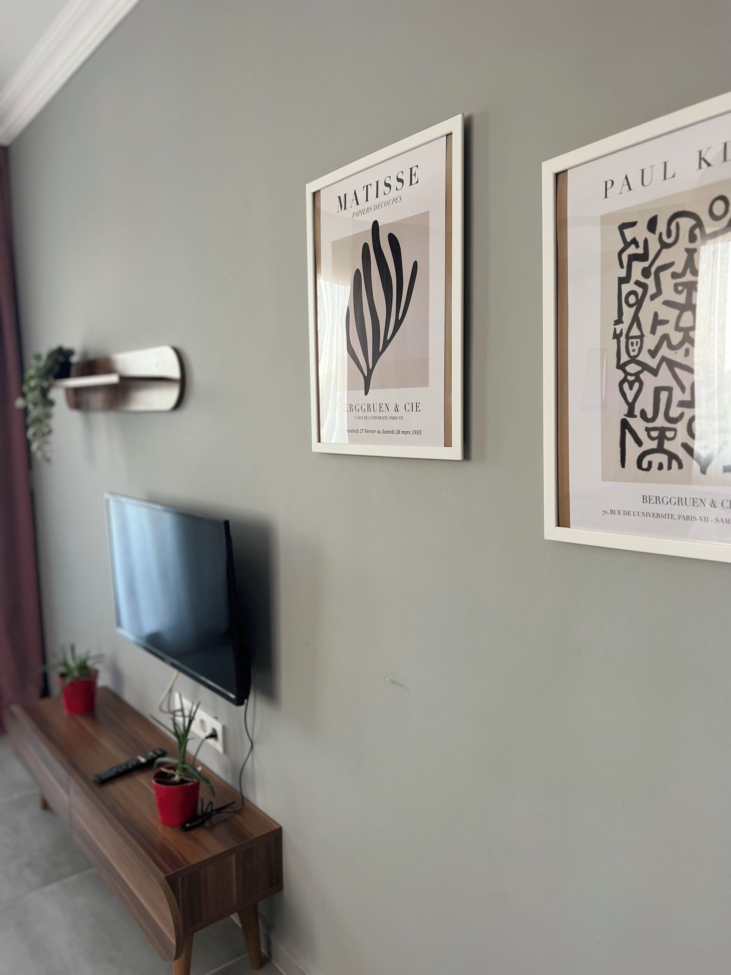 Una sala de estar moderna con un televisor de pantalla plana, un banco de madera y dos obras de arte enmarcadas en la pared.