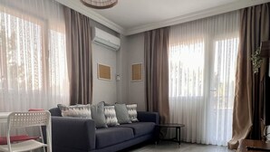 Un soggiorno moderno con un divano, una poltrona bianca, un tavolino e una lampada a sospensione.