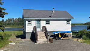 A small house with a dock and a canoe, located near a body of water.