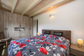 Een slaapkamer met een bed, een houten garderobe, nachtkastje en een nachttafel.