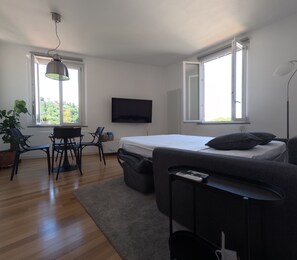 A modern bedroom with a bed, a TV, a desk, and a chair.