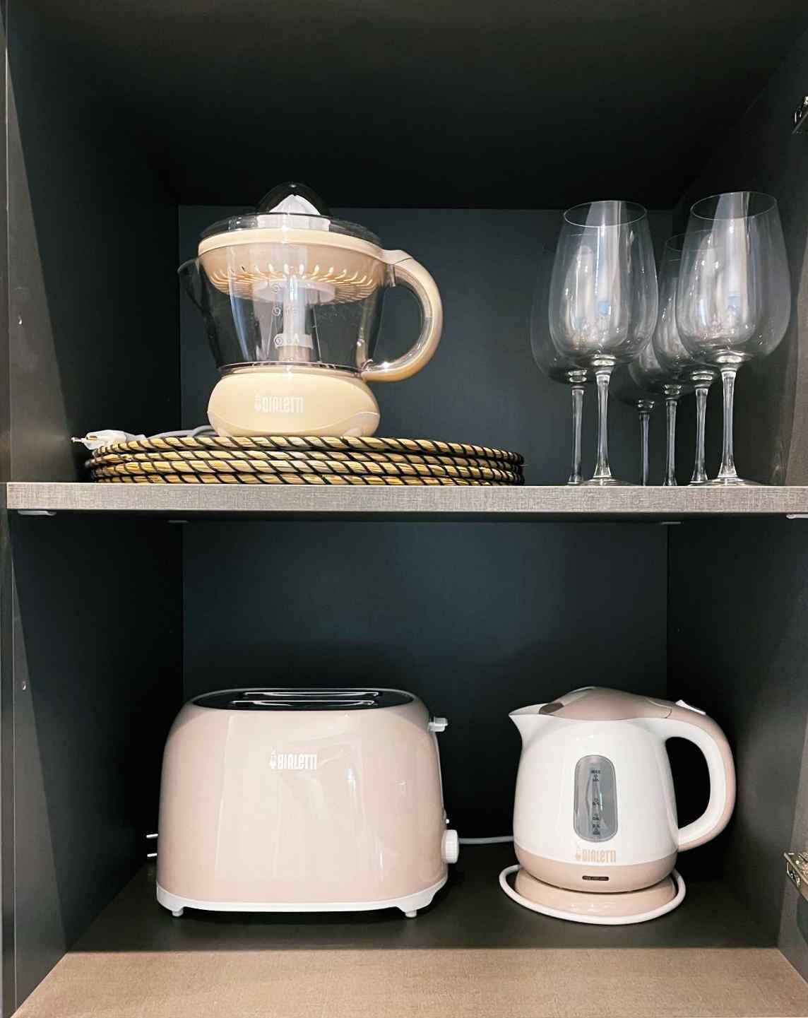 Een keuken met een broodrooster, een waterkoker en een glazen karaf op een geweven mat.