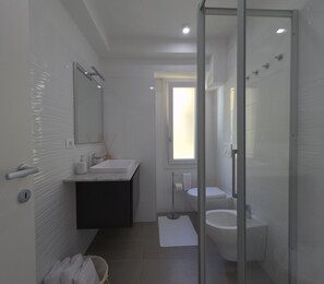 Une salle de bain moderne avec une douche à parois de verre, un lavabo et des toilettes.