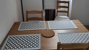 A dining table with four chairs, two placemats with geometric patterns, and a cork coaster. - Large apartment 1st floor (Saint-Pol-de-Léon)