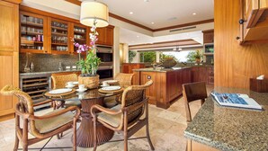 Una cocina amplia con armarios de madera, encimera de granito y un comedor con sillas de mimbre y una mesa de vidrio.