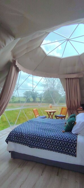 A bedroom with a large window, a bed, a chair, and a small table. - Berry Dome (Saint-Priest-la-Marche)