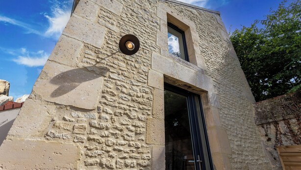 A stone building with a large window and a door.