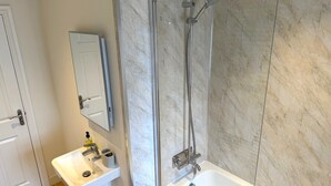 Un baño con ducha, lavabo y espejo.