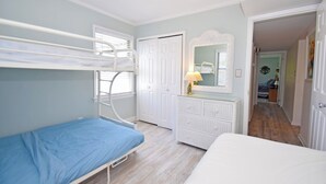 Ein Schlafzimmer mit Etagenbetten, einem Schminktisch, einem Spiegel und einer Tür zu einem weiteren Raum.