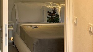 Une chambre à coucher avec un lit, des oreillers, une table de chevet et une lampe fixée au mur.