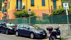 Un immeuble jaune à plusieurs étages, doté de balcons, avec un panneau indiquant un parking et un scooter garé devant.