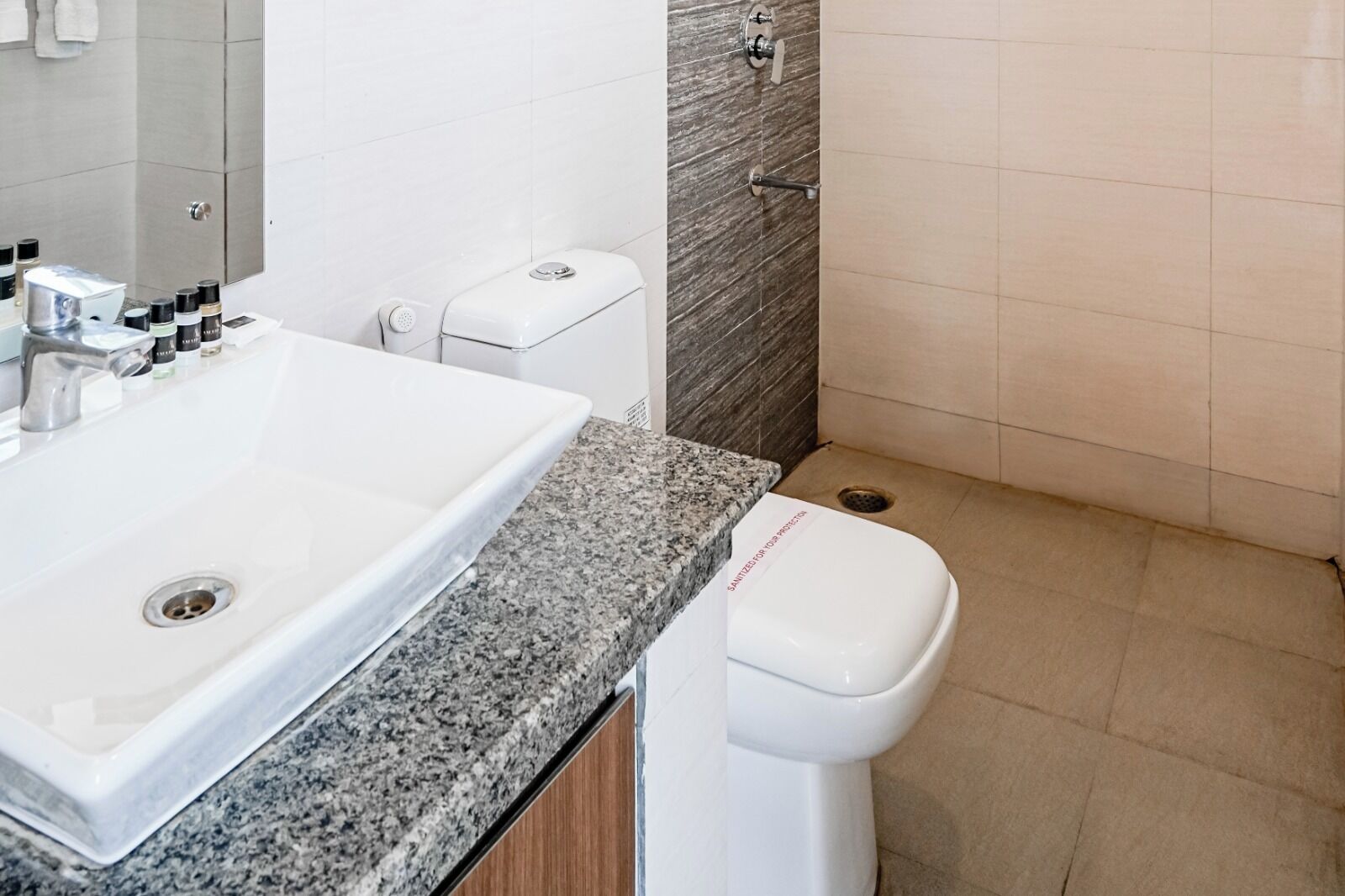 A modern bathroom with a granite countertop, a white sink, and a toilet.