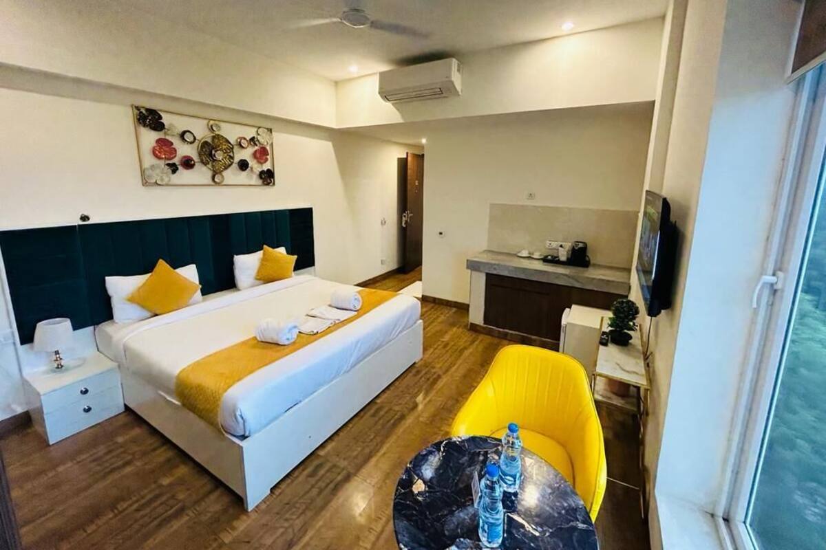 A hotel room with a bed, a desk, a chair, and a window.