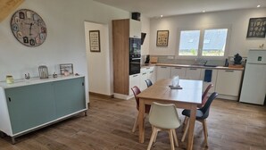 A modern kitchen with a dining table, chairs, and a clock on the wall.