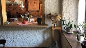 A rustic kitchen with wooden cabinets, a tiled backsplash, and a small island with a vase of dried flowers. - L'art de Vivre Avec la Nature (Fillinges)
