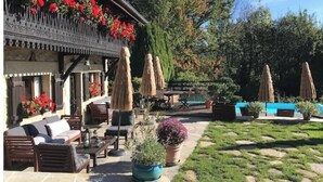 An outdoor seating area with wooden furniture, potted plants, and umbrellas. - L'art de Vivre Avec la Nature (Fillinges)