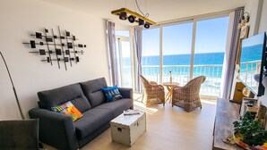 A modern living room with a grey sofa, wicker chairs, a small table, and a large window overlooking the sea. - Front line apartment at Arenal Beach (Calpe)