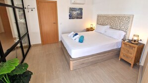 A neatly arranged bedroom with a bed, bedside tables, a ceiling fan, and a large window. - Front line apartment at Arenal Beach (Calpe)