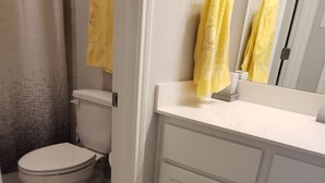 A bathroom with a toilet, a sink with a mirror, and yellow towels hanging on the wall. - Furnished clean newly room. No pet, smoking or party (Jarrell)