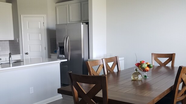 A modern kitchen with a central island, stainless steel appliances, and a dining area with wooden chairs and a table. - Furnished clean newly room. No pet, smoking or party (Jarrell)