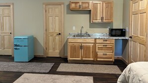 A compact kitchen with wooden cabinets, a built-in microwave, and a vintage blue refrigerator.