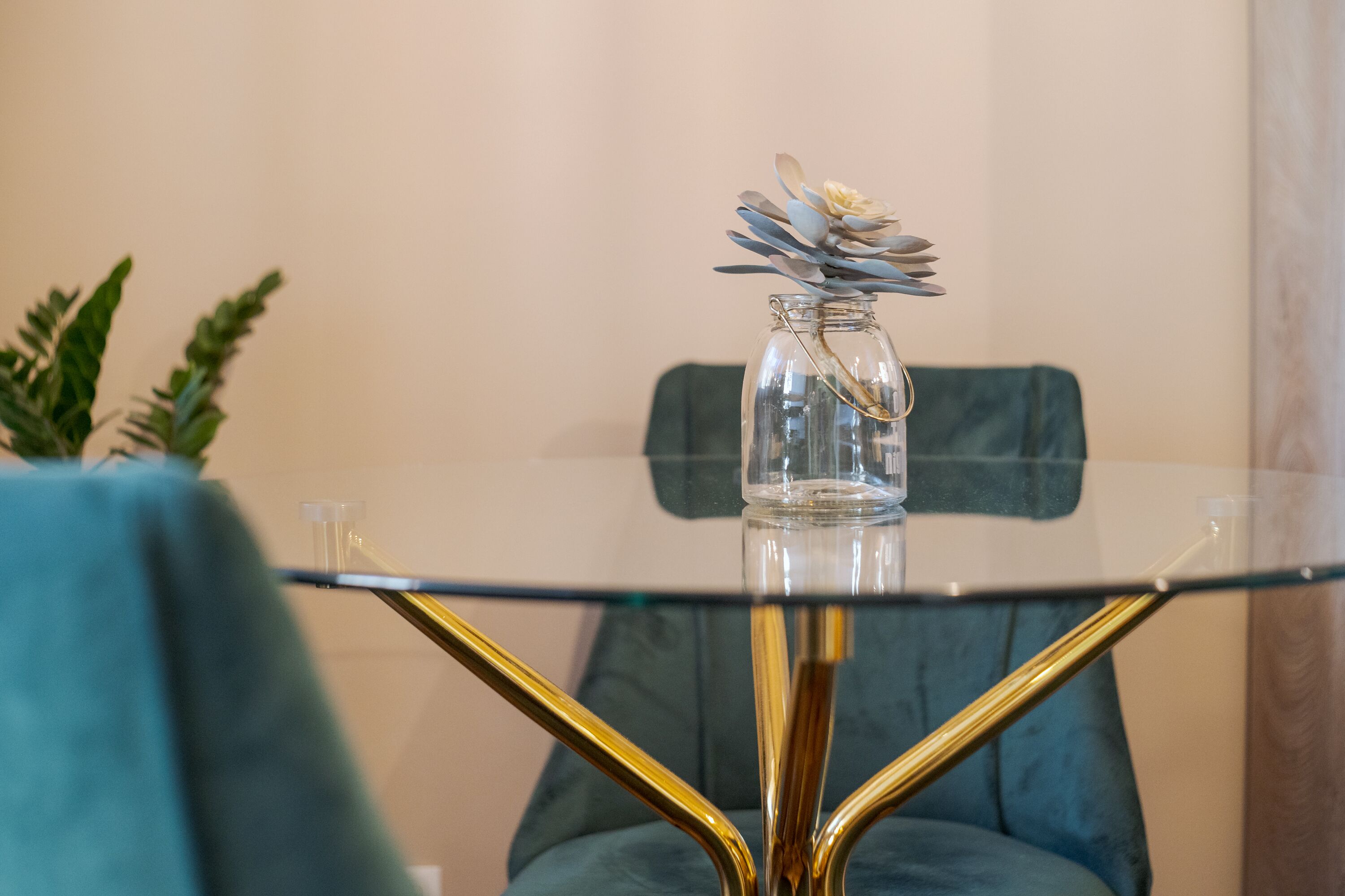 A glass table with a clear vase containing a flower arrangement.