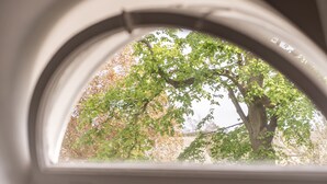 Une fenêtre donnant sur un arbre et un immeuble.