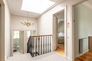 Ein Schlafzimmer mit Dachfenster, einer Chandelüster, einer Holztreppe und einer Heizkörper.
