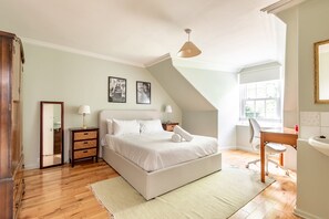 A bedroom with a large bed, a desk, a chair, a dresser, and a window. - House on the Burn (St Andrews)