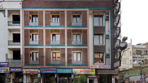 Een meerlaags gebouw met diverse winkels op de begane grond, waaronder een hotel genaamd 'HOTEL REVELS'.