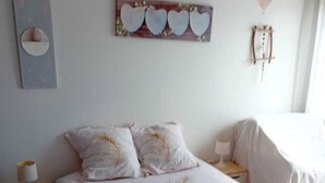 A bedroom with a large bed, two bedside tables, a wall-mounted light, and a decorative heart-shaped wall hanging. - Cosy villa in a cul-de-sac, not overlooked. (Gignac)