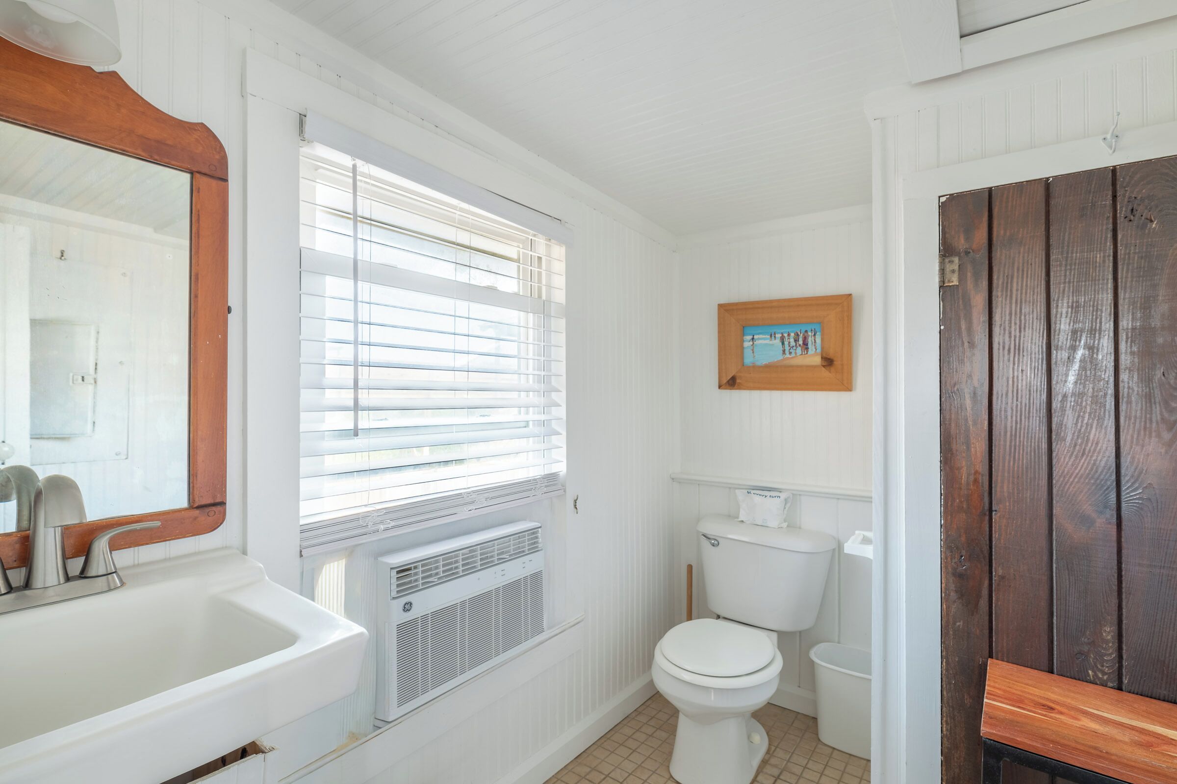 A bathroom with a white sink, a toilet, and a window with blinds.
