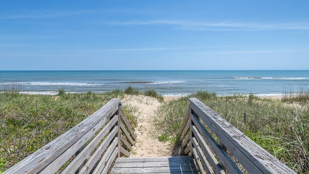 A wooden boardwalk leading to a beach with a clear view of the ocean. - The Minor Manor - NH MP 11.5, Historic Oceanfront, Dunetop Deck, YR Flex Stays (Nags Head)