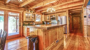 A rustic wooden cabin with a large kitchen area featuring a central island, wooden cabinets, and a stainless steel refrigerator. - 3C Ranch on the Road to Yosemite (Groveland)