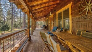 A covered wooden deck with a table and chairs, large windows, and a compass on the wall. - 3C Ranch on the Road to Yosemite (Groveland)