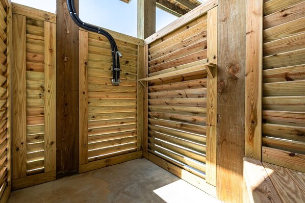 Eine Holzhütte mit geneigtem Dach, einem sichtbaren schwarzen Rohr und einem Betonboden.