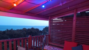 A wooden deck with a table and chairs, a bench with cushions, and a view of the sea. - 2 bedroom mobile home in saint-raphaã "l (Saint-Raphaël)