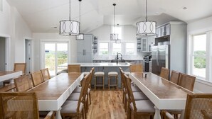 Una cucina moderna con isola centrale, tavolo da pranzo in legno e sgabelli da bar.