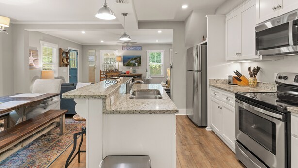 A modern kitchen with white cabinets, stainless steel appliances, and a granite countertop. - The Beach is calling you at The Porch Side Cottage, sleeps 9 (St Simons Island)