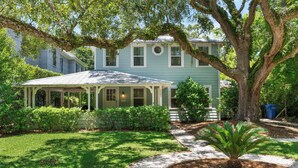 A two-story house with a covered porch, a large tree in front, and a well-maintained lawn. - The Beach is calling you at The Porch Side Cottage, sleeps 9 (St Simons Island)