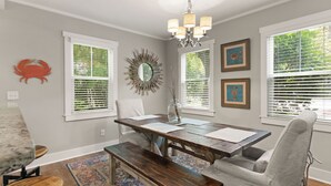 A dining area with a wooden table, benches, and a chandelier. - The Beach is calling you at The Porch Side Cottage, sleeps 9 (St Simons Island)