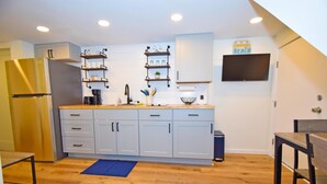 A compact kitchen with light blue cabinets, a stainless steel refrigerator, and a wooden countertop.