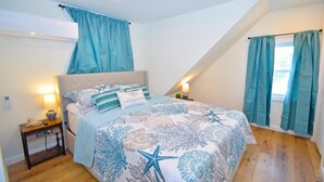 A bedroom with a bed, nightstands, a window with curtains, and an air conditioning unit.