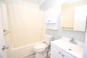 Un baño con bañera, inodoro, lavamanos y armarios.