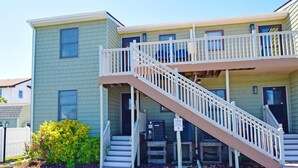 A two-story building with a balcony and a staircase leading to the entrance. - Park Place 101 2 Bedroom Condo by RedAwning (Ocean City)