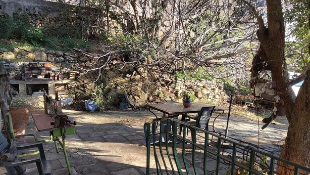 An outdoor seating area with stone flooring, metal chairs, and a table with a teapot. - Appartement Climatisé, RDC Villa, Avec Jardin Arboré. Proche Centre Ville Bastia (Ville-di-Pietrabugno)