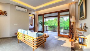 A spacious living area with a wooden bench, a balcony with a view of greenery, and a wall-mounted air conditioner.