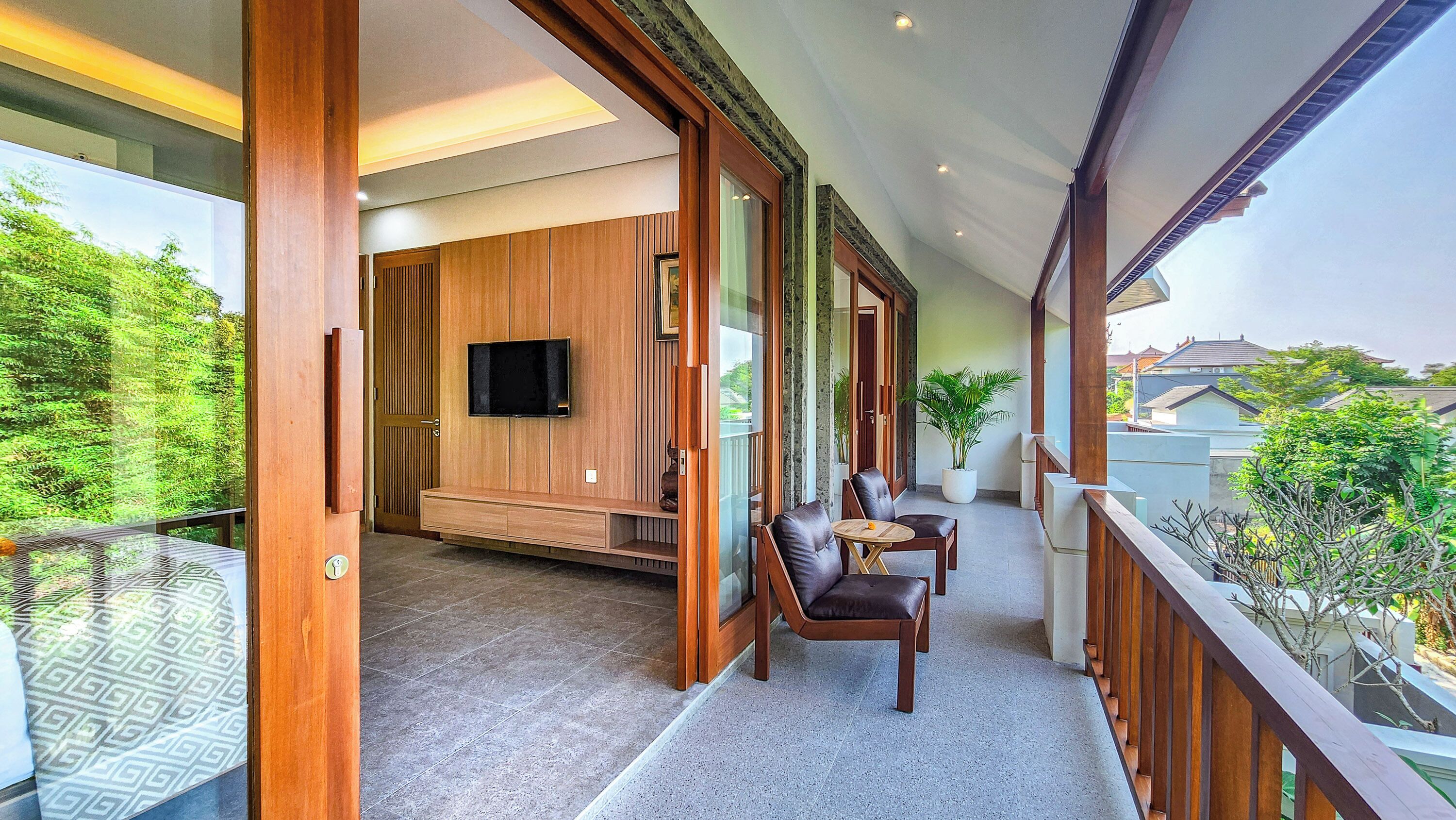 A modern living room with a TV, seating area, and a balcony with a view of the city.